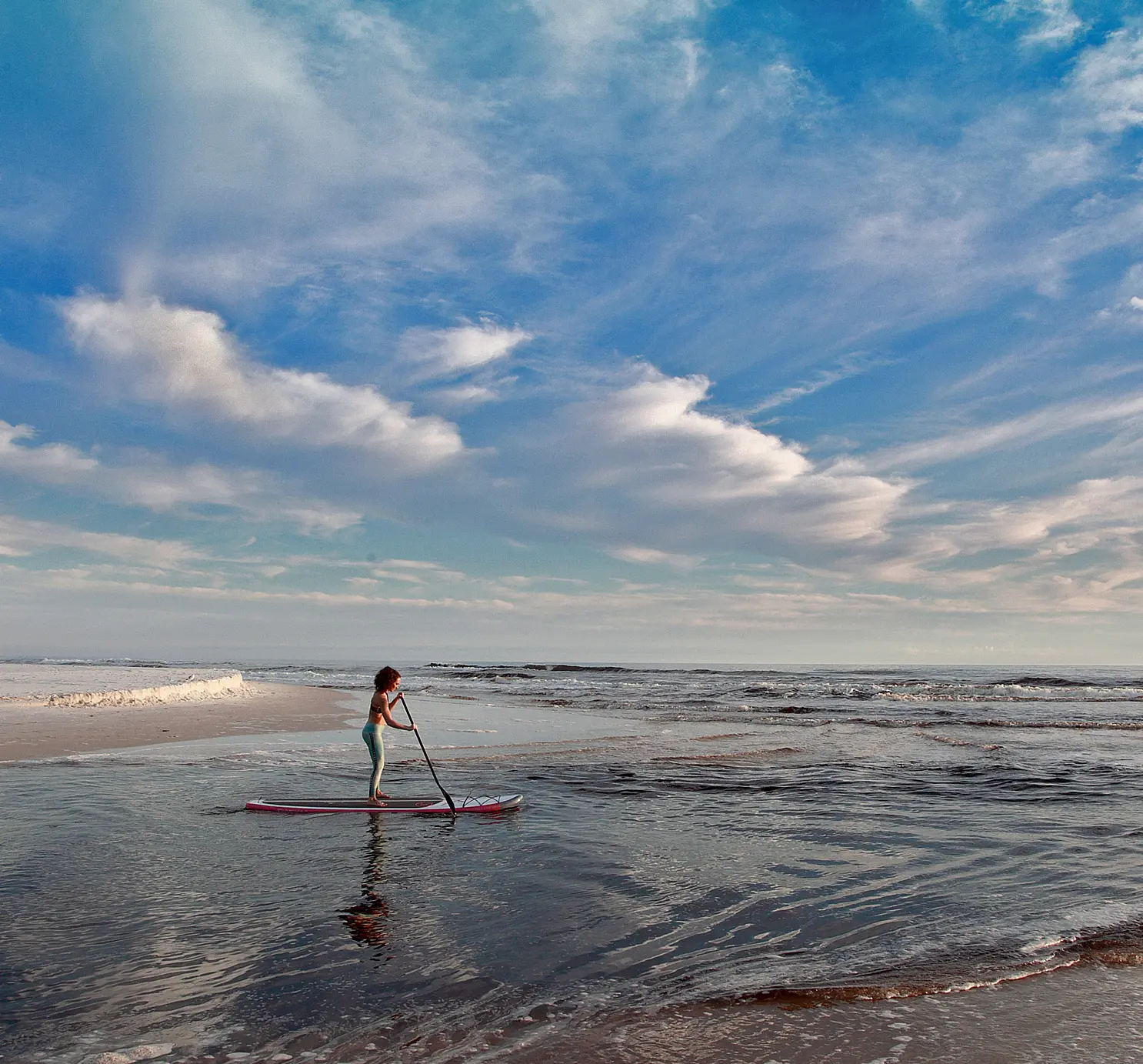 Kids paddleboarding on a northwest Florida beach