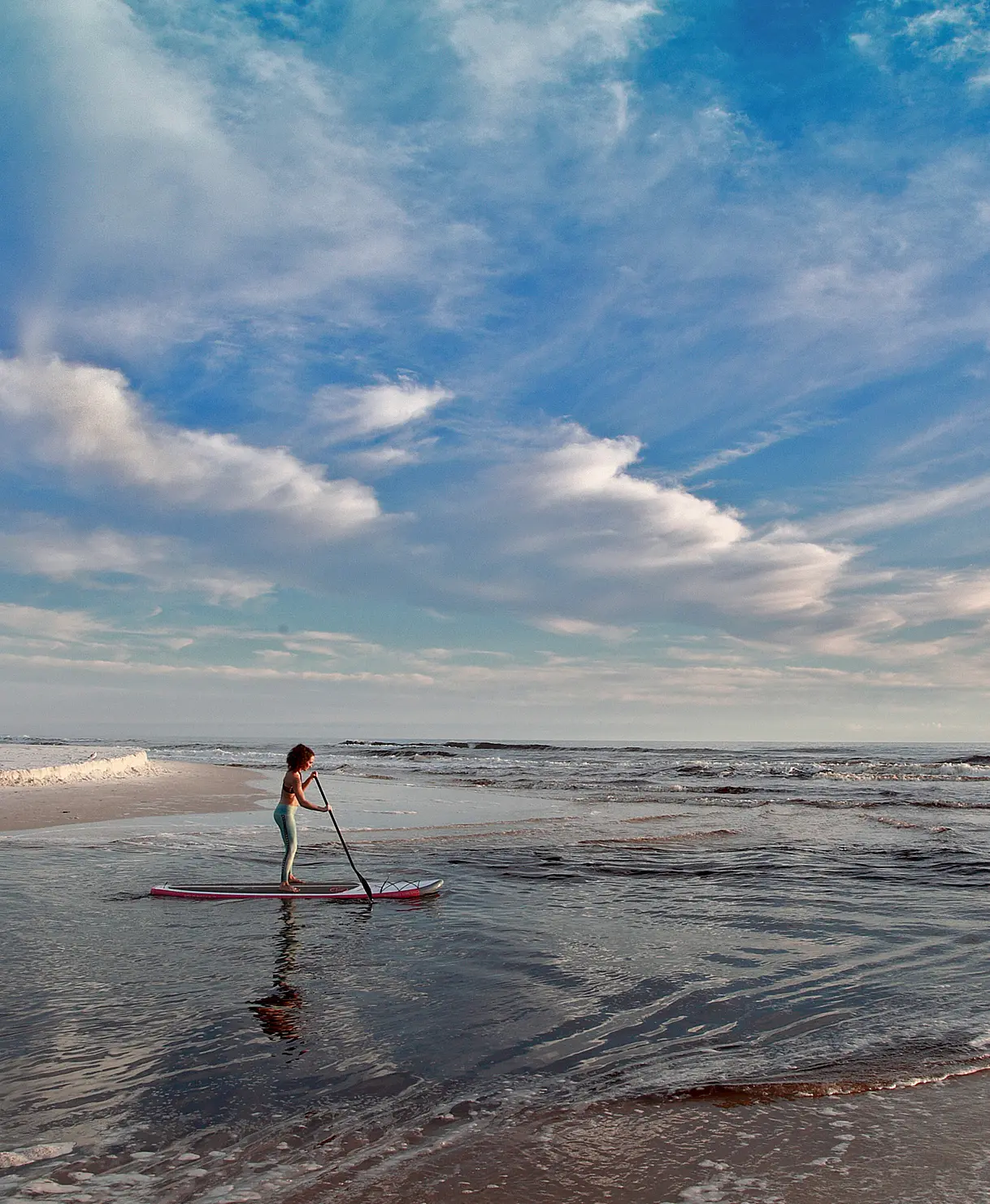 Kids paddleboarding on a northwest Florida beach